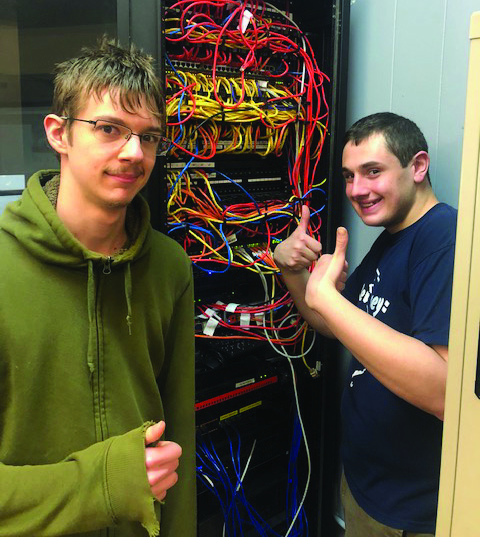 Two Chapel Hill Academy male students working with a server rack and giving thumbs up hand signals