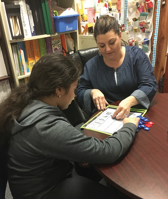 Female CHA middle school student working on reading with a female teacher