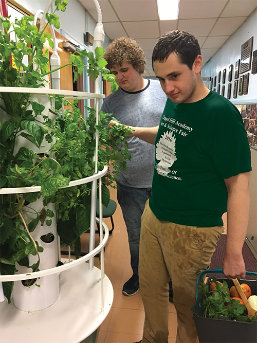 Two male CHA students working on hydroponic garden at school